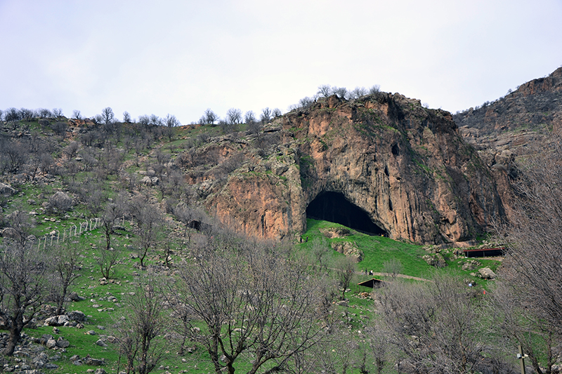 Vue sur une colline avec une grande grotte qui s'ouvre.