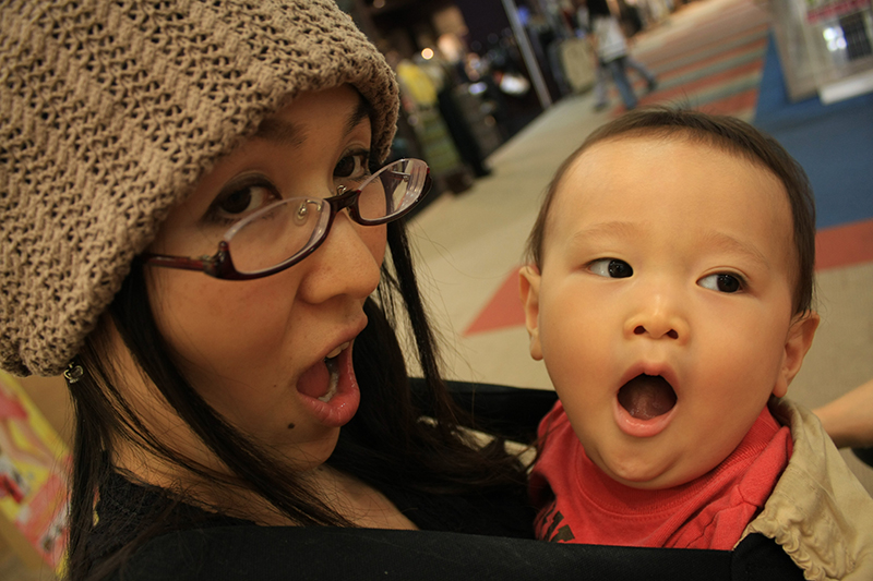 Uma mulher segurando um bebê, ambos bocejando.
