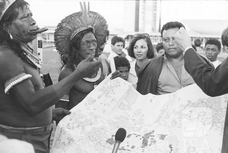 Um grupo de homens segurando um mapa e falando animadamente.
