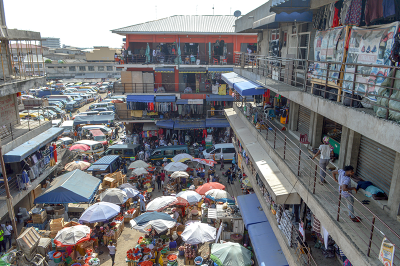 一个广场，里面有许多商人摊位，上面覆盖着雨伞。