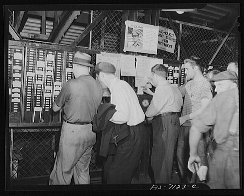 A group of male employees punching a time clock.
