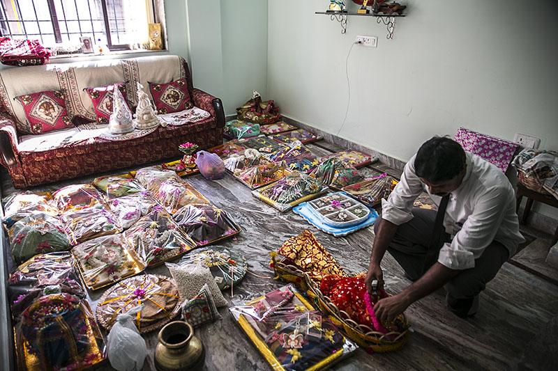 Um homem examinando muitos itens do dote de uma mulher expostos no chão de uma sala de estar.