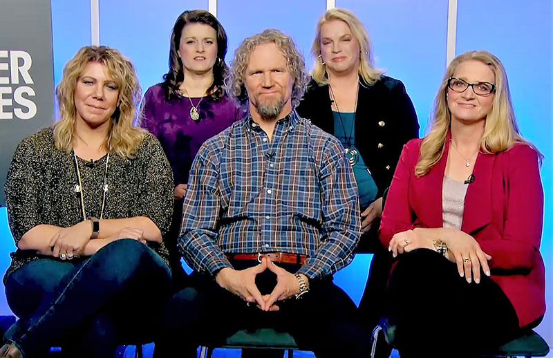 A man in a polygamous marriage surrounded by his four wives.