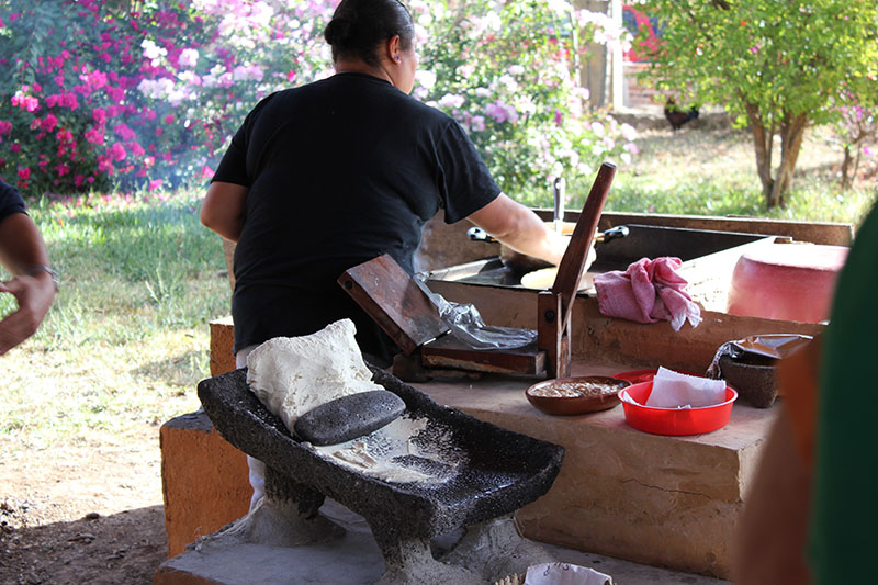 一位女士背对着镜头工作，前景中可以看到石材研磨机和磨石。