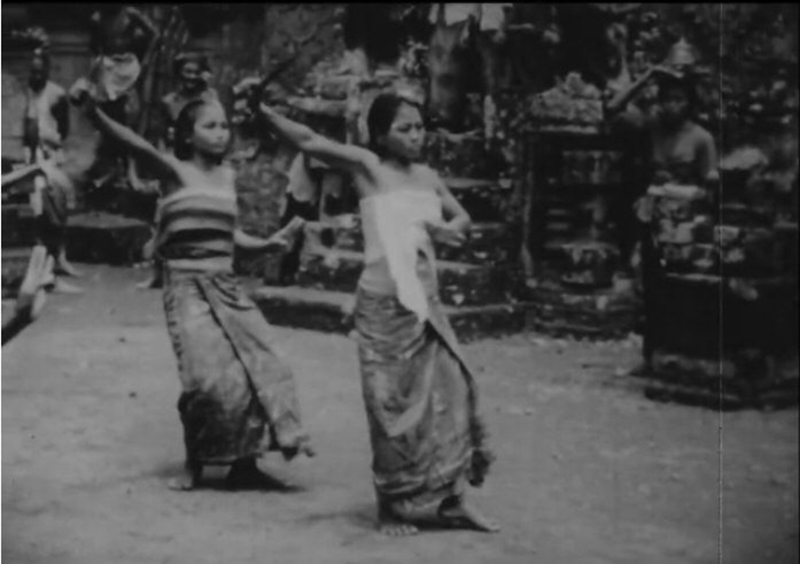 Quadro de um filme em preto e branco de duas meninas vestindo saias enroladas e fazendo movimentos de dança em uníssono.