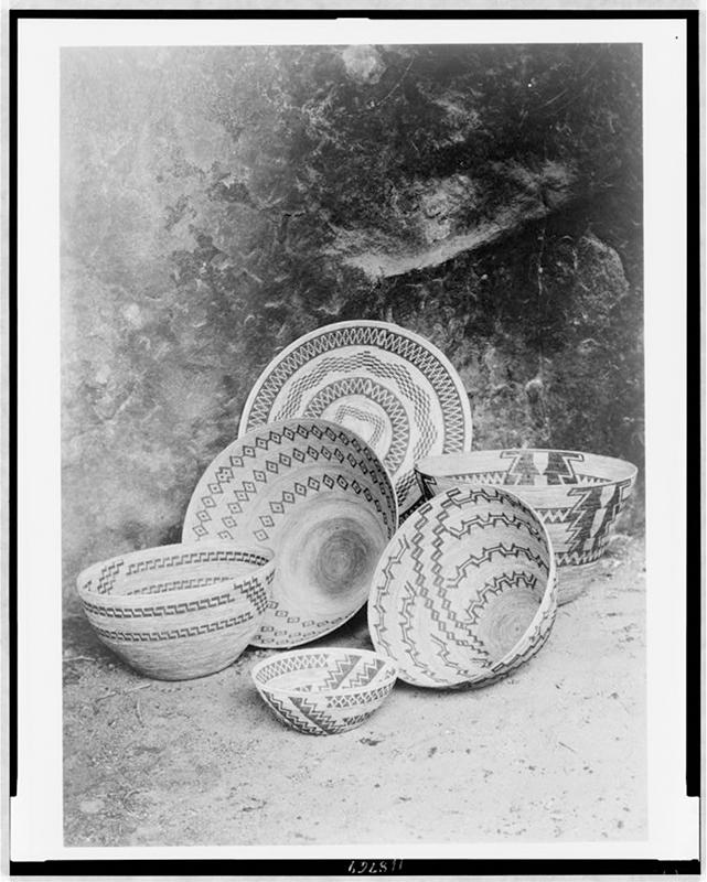 Black and white photograph of a half dozen hand-woven baskets, decorated with geometric patterns.