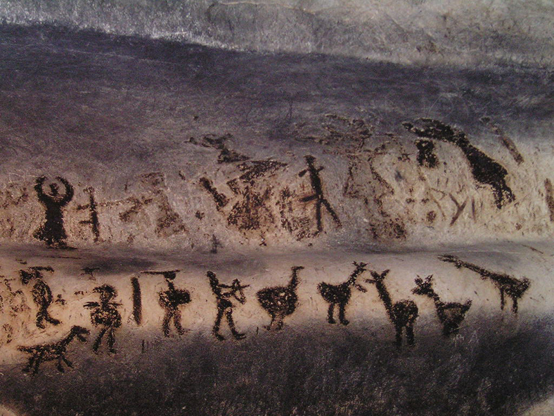 Deux rangées de figures abstraites peintes sur le mur d'une grotte.