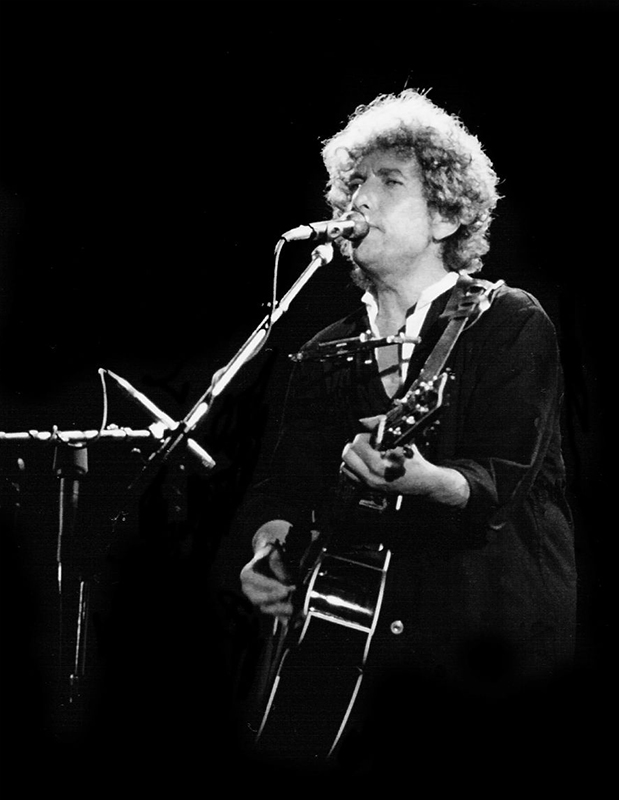 Bob Dylan kuimba na kucheza gitaa wakati wa tamasha.