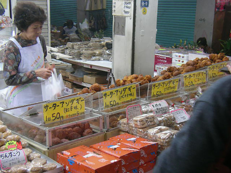 一位年长的日本女人在户外市场购物。