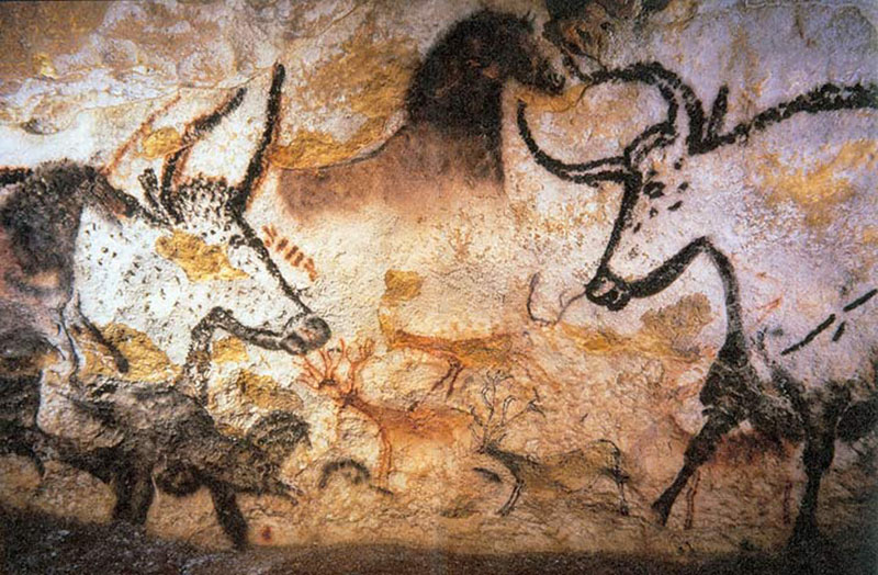 Pintura na parede de uma caverna de dois touros com chifres frente a frente. As formas dos animais são delineadas em preto contra a cor natural da pedra de fundo.
