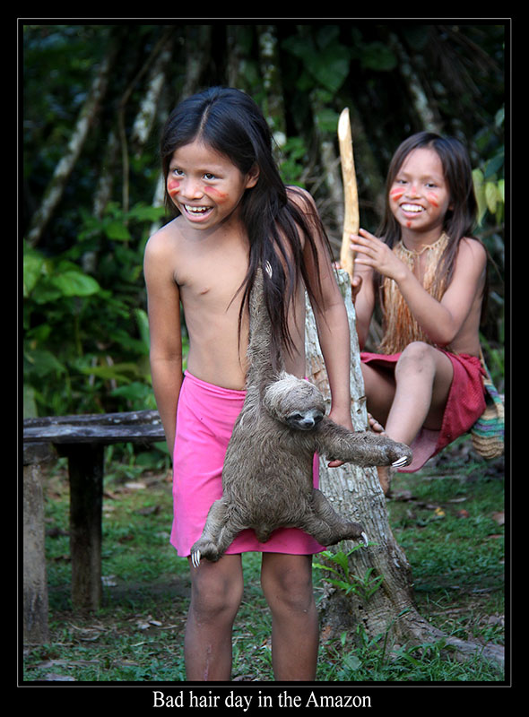 两个面带微笑的孩子，留着长长的黑发和彩绘的脸。 一个孩子的肩膀上悬挂着一只树懒。