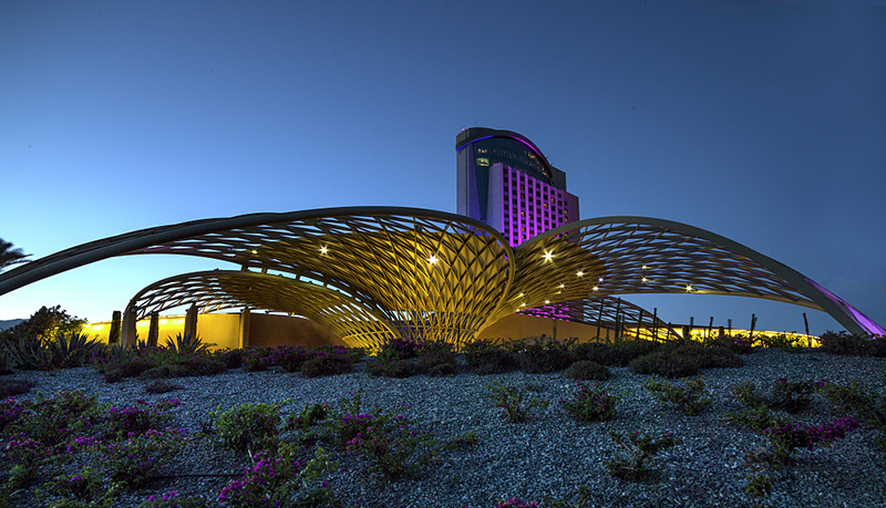 Um edifício grande e moderno em um deserto com várias estruturas em forma de asas em forma de redes ao redor.