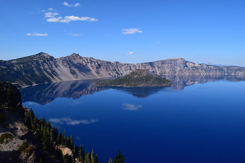 Un grand lac entouré de montagnes rocheuses, avec une petite île au centre.