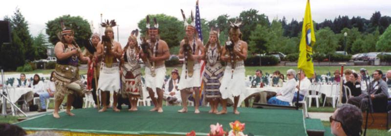 Huit danseurs en tenue traditionnelle se produisent sur scène.