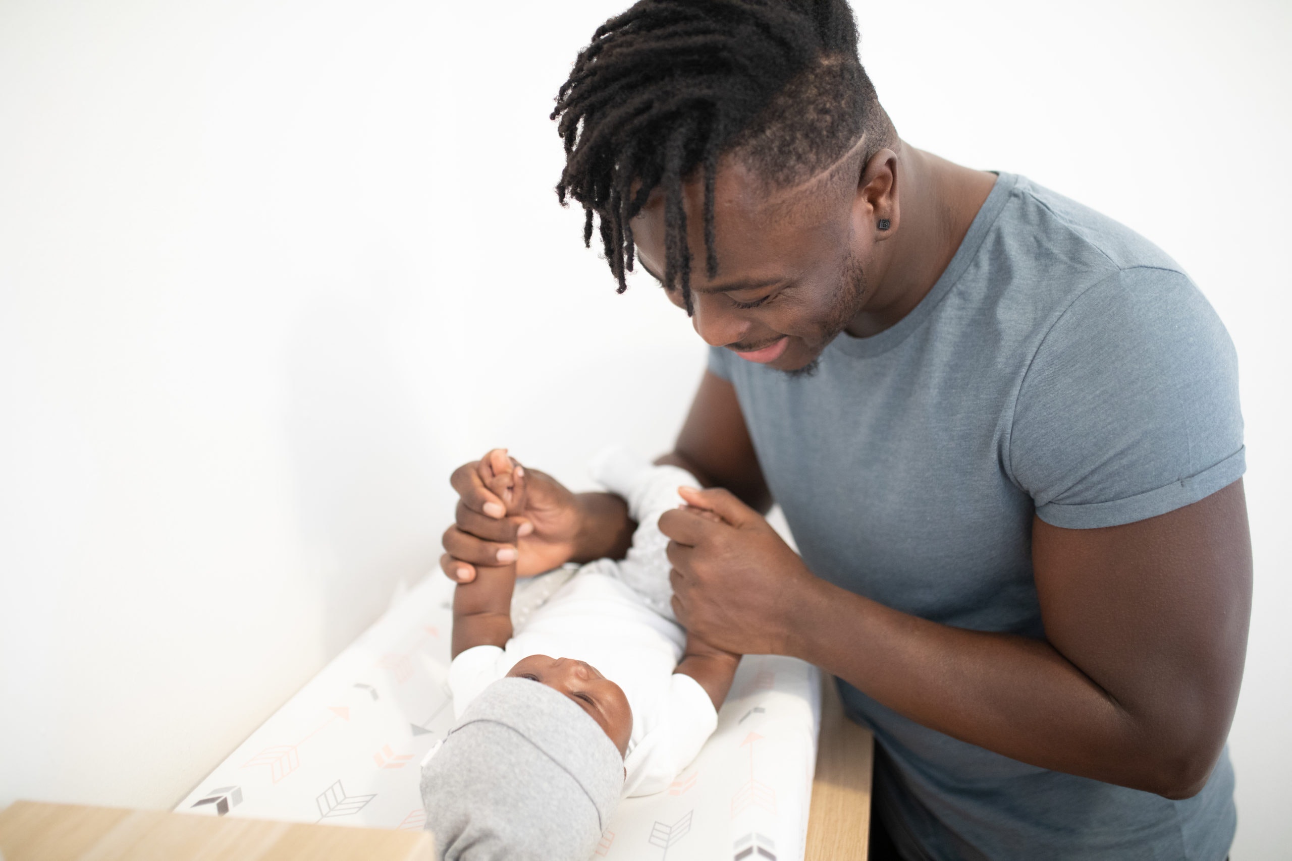 A black father playing with his infant child. 