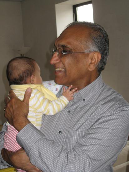 An older man holds an infant child and smiles. 