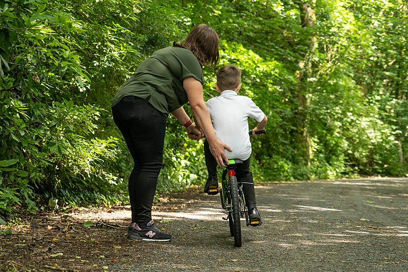 Parent helping child learning to ride a bike