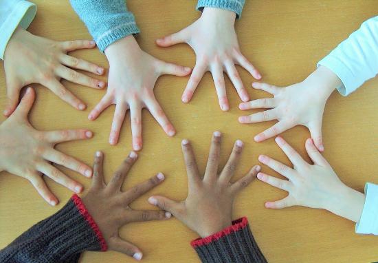 The hands of children with many different skins colors laid on a table