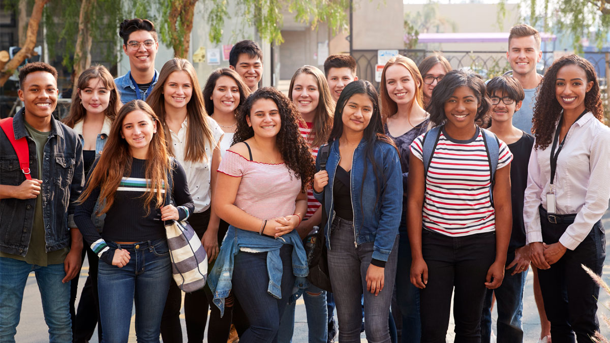 A group of teenagers of varying races and ethnicities smiling.