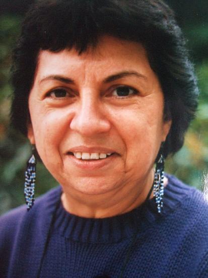 portrait of Anzaldúa who is smiling, wearing a blue sweater