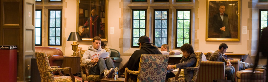 Students studyiing in easy chairs in the living room of a dorm