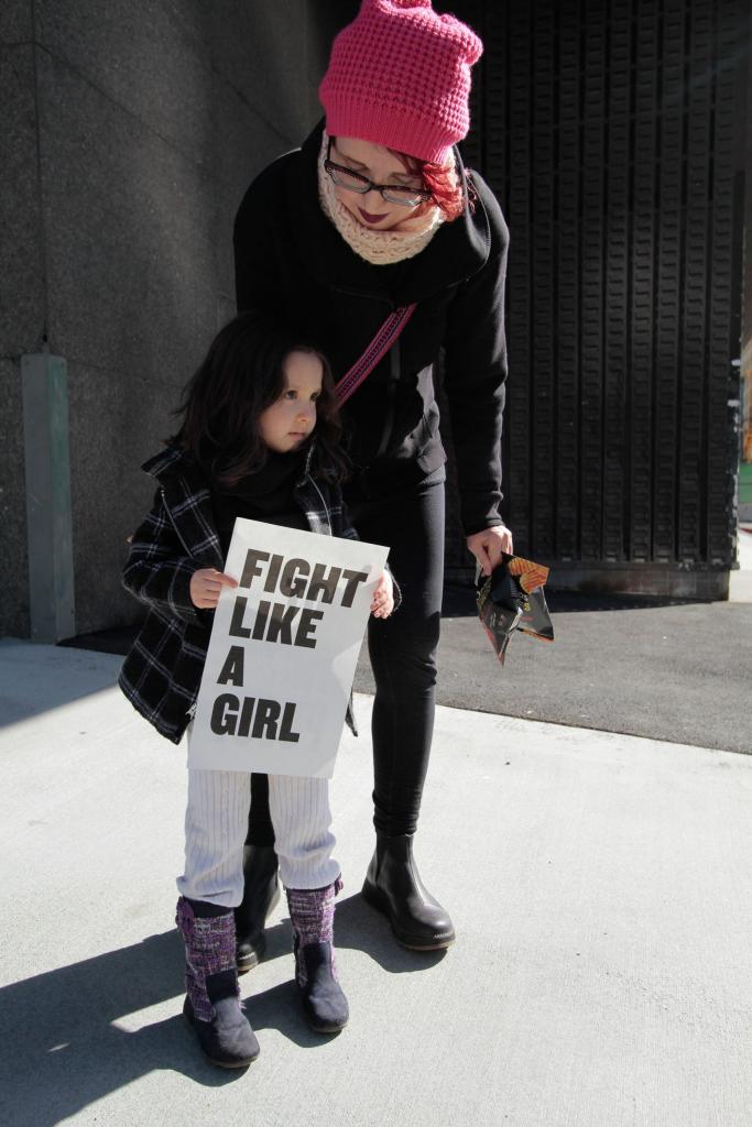 girl holding sign that reads 'Fight like a girl'