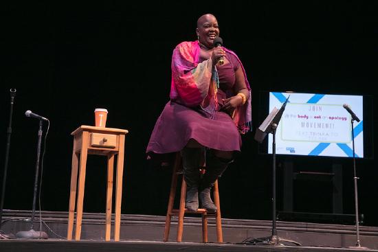 Sonya Renne Taylor laughing while presenting on a stage