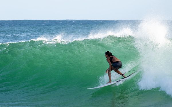 Una mujer con pantalones cortos negros surfeando una ola.