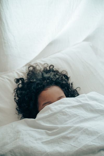 A person sleeping under a blanket.