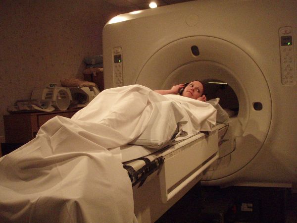 Una mujer acostada y preparándose para ingresar a una máquina de resonancia magnética.