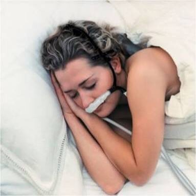 Una mujer durmiendo en la cama con un dispositivo de CPAP en la nariz.