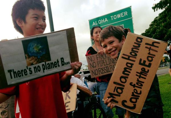 Niños en Hawái exhiben letreros protestando por el oleoducto Dakota Access y un letrero dice mālama honua, cuida la tierra.