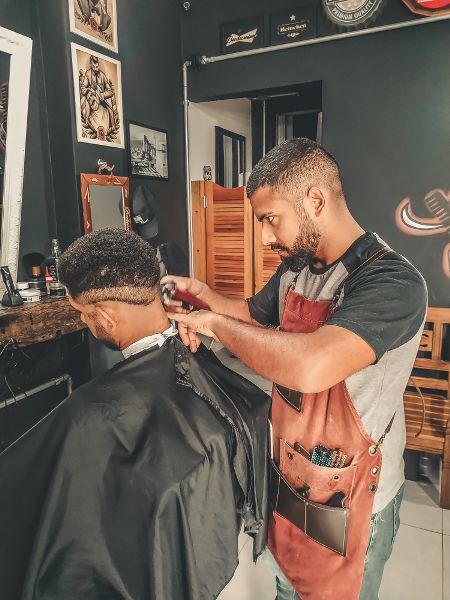 A barber is trimming a man’s hair.