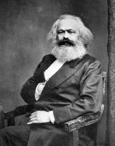 Black and white image of Marx sitting in a chair.