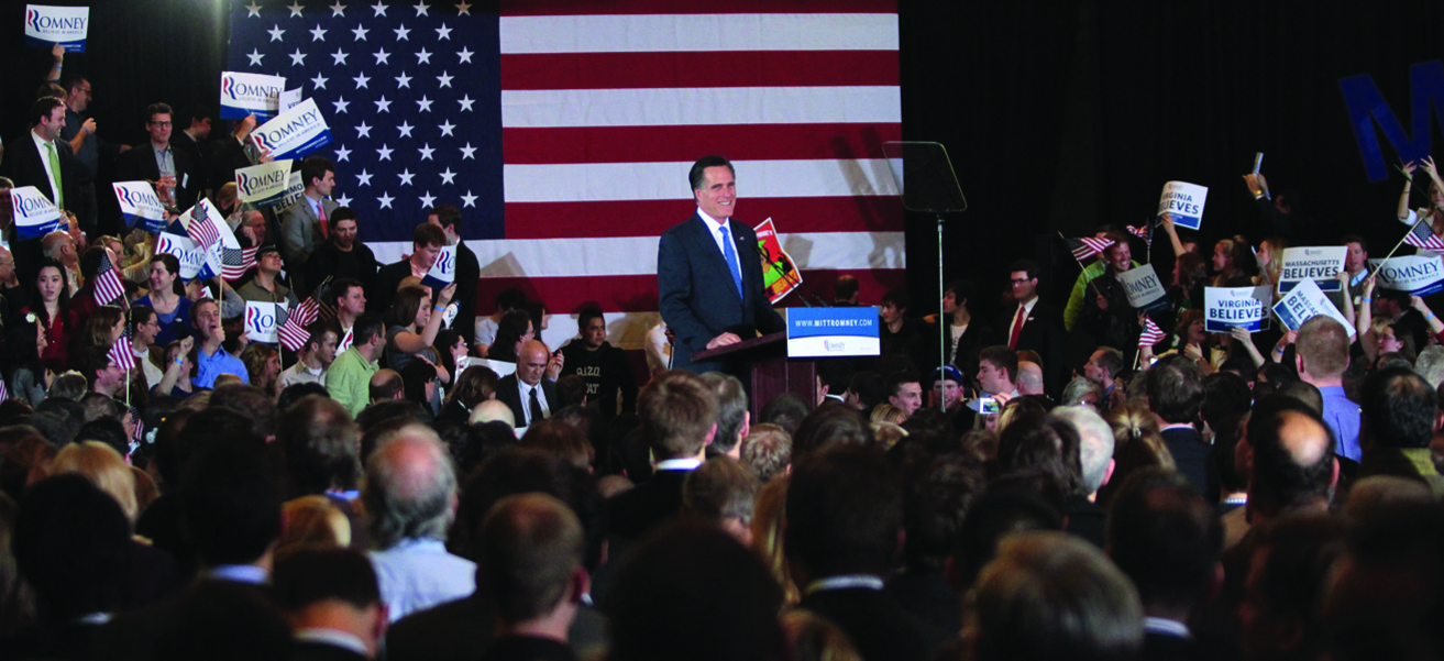 Foto de Mitt Romney na frente de uma multidão, sorrindo.