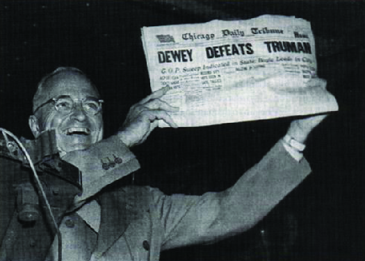 A foto mostra Harry S. Truman exibindo um jornal cuja manchete diz “Dewey derrota Truman”.