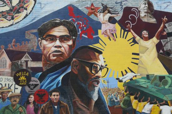 A mural with faces of Philip Vera Cruz, Larry Itliong, and Cesar Chavez and protestors marching for the strike
