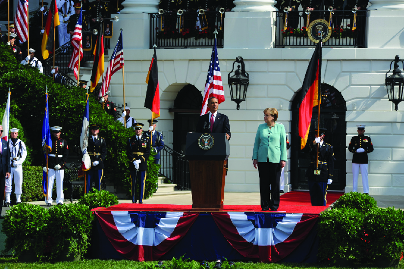 Une photo de Barack Obama s'exprimant devant la Maison Blanche. Angela Merkel se tient à côté de lui.