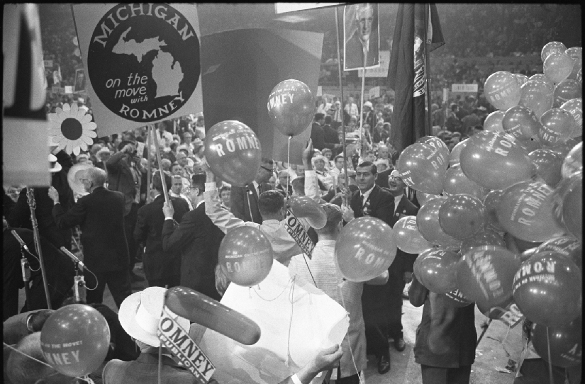 Uma foto da convenção nacional republicana em 1964. As pessoas seguram cartazes e balões em apoio a George Romney.