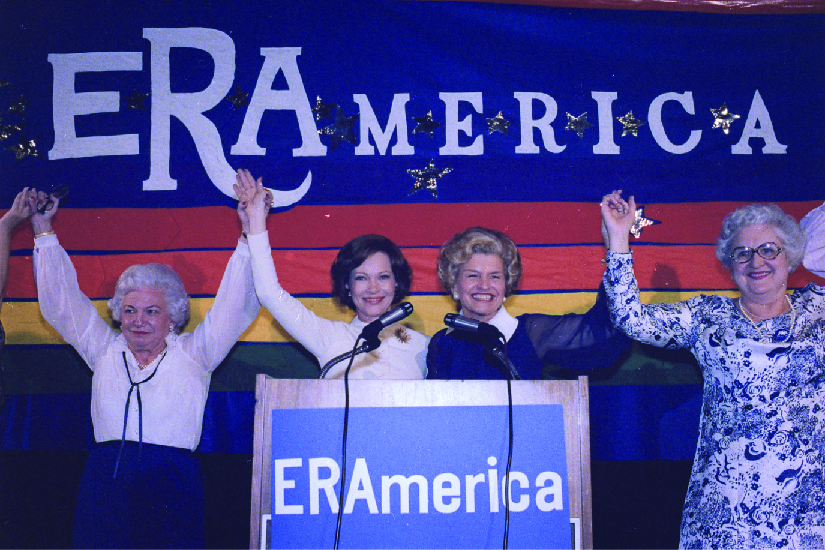 罗莎琳·卡特和贝蒂·福特在支持《平等权利修正案》的集会上发言的照片。 舞台上的标语写着 “erAmerica”。