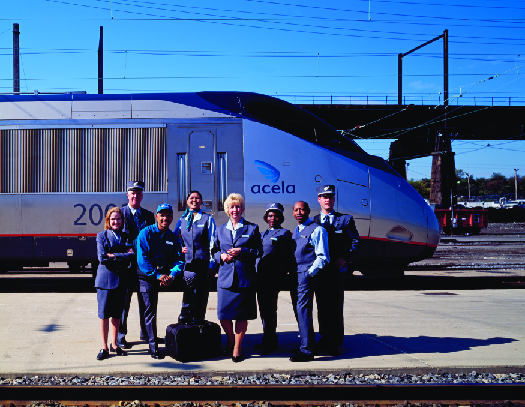 一张Amtrak工作人员在火车经过他们身后时站在火车站台上的照片。