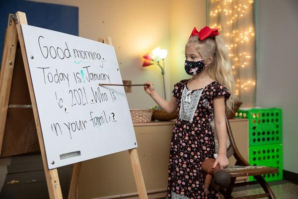 Un niño señala cada palabra del mensaje matutino en la pizarra.