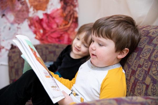 Dos niños leen un libro juntos.