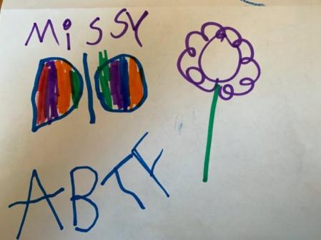 La escritura del niño tiene el nombre Missy en la esquina superior izquierda. Hay una imagen de una colorida mariposa bajo “Missy” y una flor junto a la mariposa. “ABTF” se escribe debajo de la mariposa en mayúsculas.