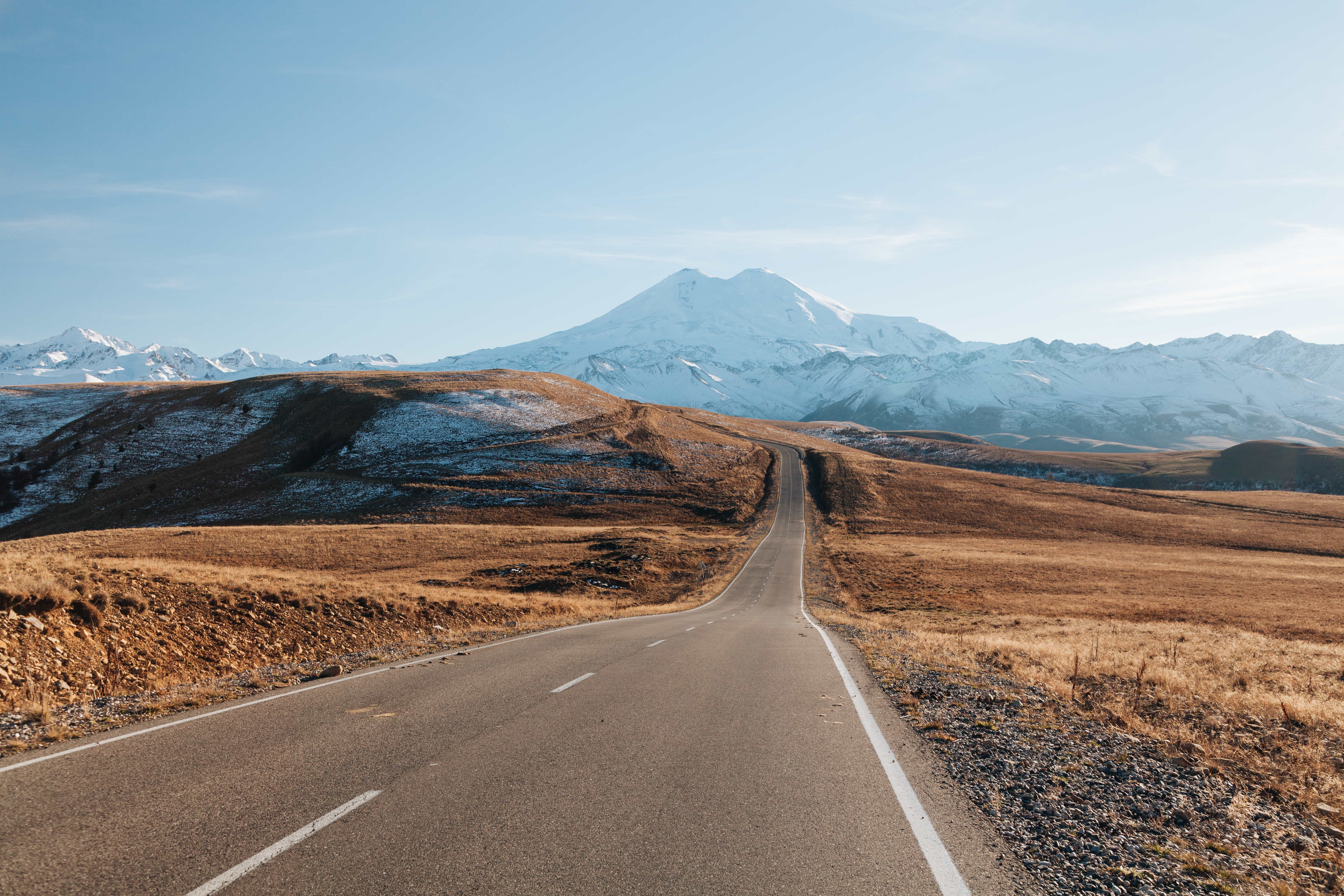 Two line highway leading to snow-covered mountain