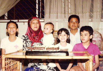 A family with parents and children sit on the floor at a table