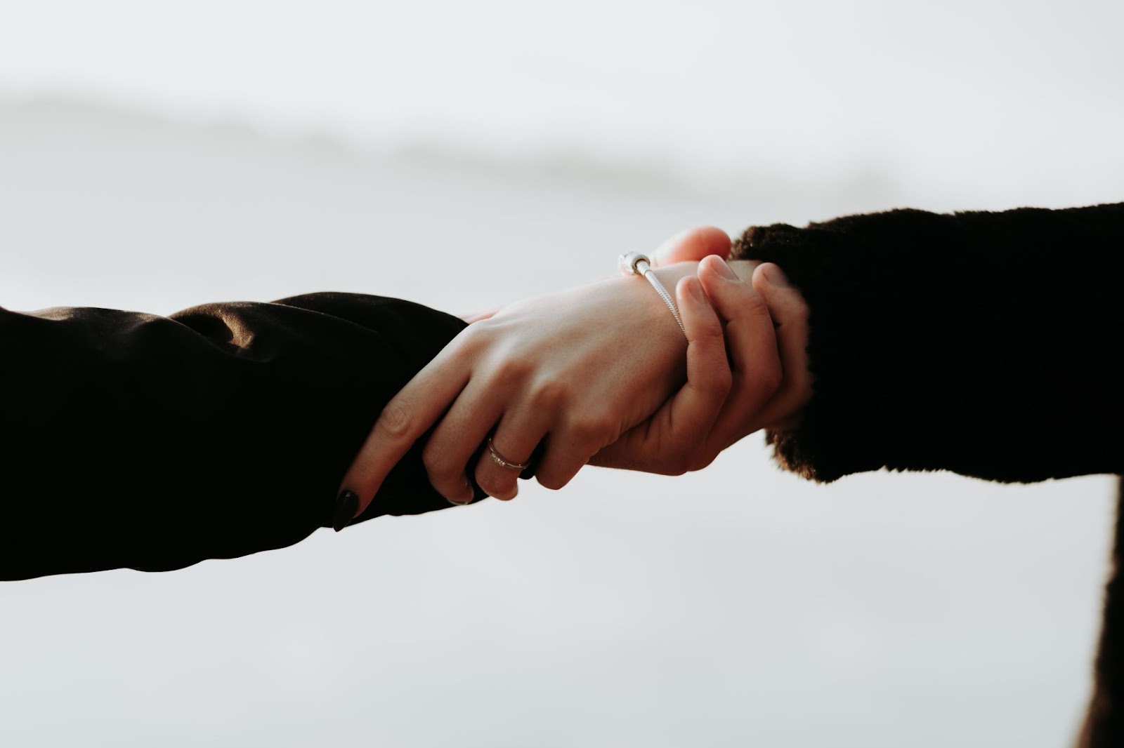 Hands of two people gently wrapped around each other&rsquo;s wrists
