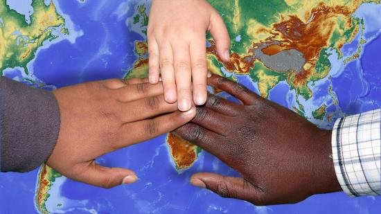 Three children's hands on a map, representing Black, brown, and white people