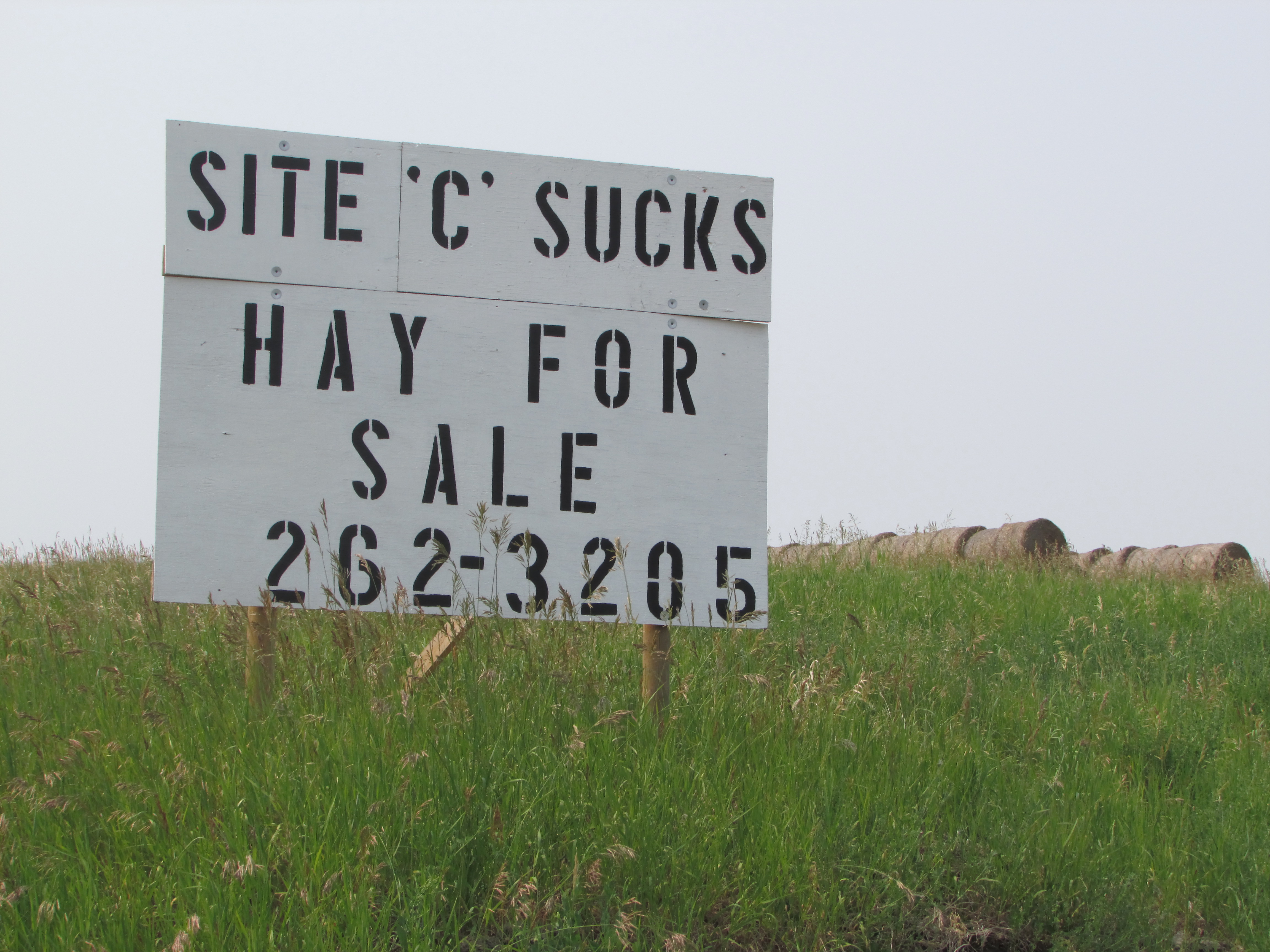 Sign in a grassy field with hay bales in the background