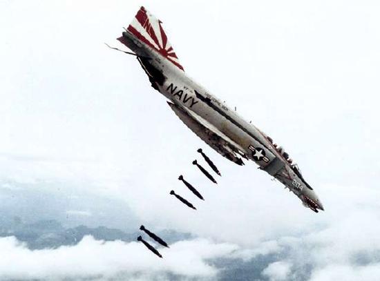 a navy fighter plane drops multiple bombs over Vietnam